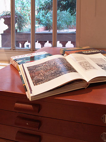 Libros de arte abiertos sobre un mueble con ventada que da al patio